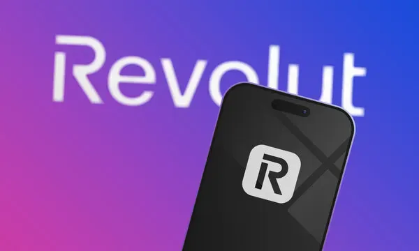 The Revolut wordmark behind a phone showing the Revolut app icon