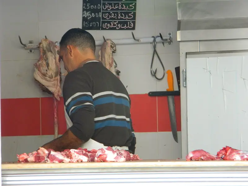 A butcher cutting meat at his shop counter in Tunisia
