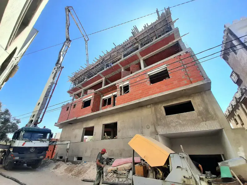 A concrete pump pouring a floor slab on a block of flats under construction in Tunisia
